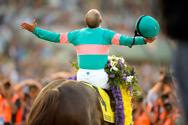 Zenyatta and jockey with his arms outstretched.